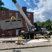 grey generator being lifted by big crane