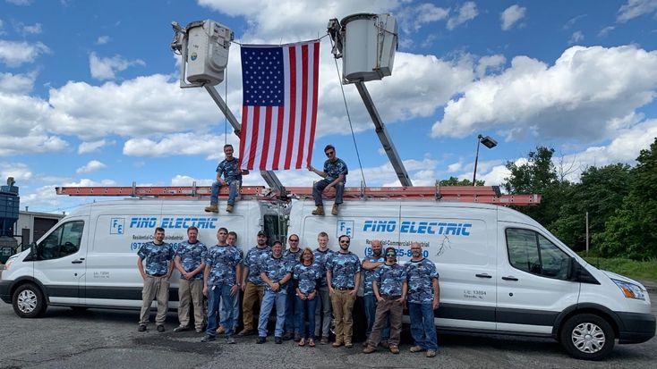 fino electric team in front of fino electric vans with american flag waving above